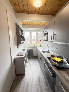 a kitchen with white cabinets and a wooden ceiling at Ferienwohnung Heimat auf Zeit Pellworm in Pellworm