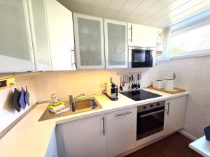 a small kitchen with white cabinets and a sink at Blaue Dören in Langeoog