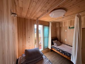 a bedroom with wooden walls and a bed with a window at Bangdigareum B&B in Seogwipo