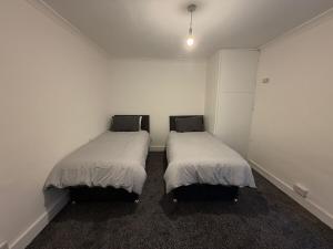 two beds in a room with white walls at Central Luton, Guest House, Contractor Friendly, Long Stays Welcome in Luton