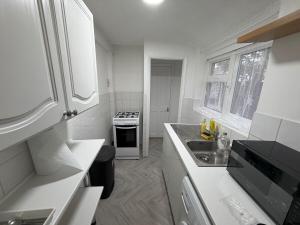 a white kitchen with a sink and a stove at Central Luton, Guest House, Contractor Friendly, Long Stays Welcome in Luton