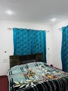 a bedroom with a bed with blue curtains at Gulmarg serenity in Khor