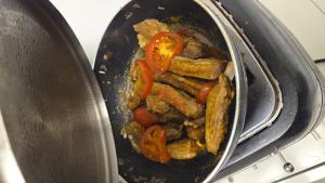 a pan full of food with tomatoes and meat at Casa LarisaAndrei in Bîrsău +2 photos