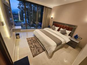 a bedroom with a large bed and a large window at Nirvana Bliss By Cosy Homes, Malsi in Dehradun
