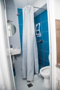 a bathroom with a white shower curtain and a toilet at Ξενώνες Ανεμόμυλοι - Windmills Hotel in Panayía +9 photos