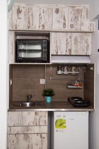 a small kitchen with a microwave and a sink at Ξενώνες Ανεμόμυλοι - Windmills Hotel in Panayía