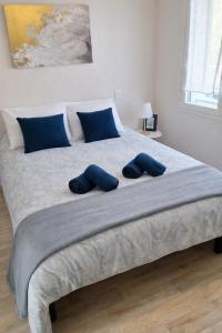 a large bed with two blue pillows on it at T3 centre La Teste-de-Buch Terrasse 2 parkings Wi-Fi fibre 4 pers in La Teste-de-Buch