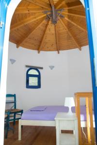 a bed in a room with a wooden ceiling at Ξενώνες Ανεμόμυλοι - Windmills Hotel in Panayía