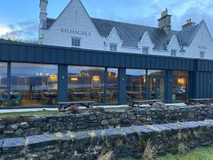 a building with a stone wall in front of it at Balmacara Hotel in Kyle of Lochalsh