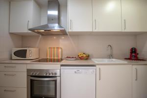 a kitchen with a stove and a sink and a microwave at Sweet Inas in Sitges