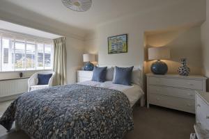 a bedroom with a bed and a dresser and a window at Haven House in Lymington