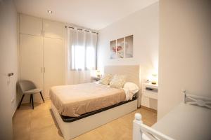 a white bedroom with a bed and a chair at Sweet Inas in Sitges
