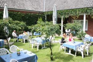 a group of people sitting at tables in a garden at Hotel Zum Ratsherrn in Lübeck