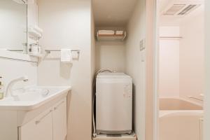 a small white bathroom with a sink and a refrigerator at SAIEI Hotel 东京小岩 JR京成双站直达成田羽田迪士尼适合家庭团队整栋多房型 in Tokyo +152 photos