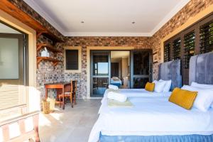 two beds in a room with a brick wall at Seemeeu, Gouritsmond in Gouritzmond