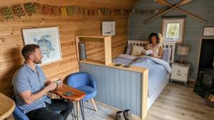 a man and a woman in a tiny house bedroom at Emlyn's Coppice - Luxury Woodland Glamping in Holywell
