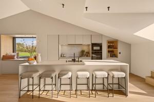 a kitchen with a white island with stools at Lakeside Lodges - Gîte 6 personnes à 10 min circuit Spa Francorchamps in Jalhay