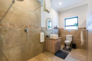 a bathroom with a shower and a toilet and a sink at Seemeeu, Gouritsmond in Gouritzmond +32 photos