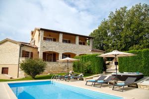 a house with a swimming pool with chairs and umbrellas at Villa Vernier by IstriaLux in Kringa