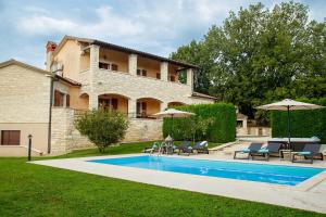 a house with a swimming pool with chairs and umbrellas at Villa Vernier by IstriaLux in Kringa