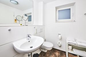 a white bathroom with a sink and a toilet at ADAPT APARTMENT HOTEL Giessen in Gießen +21 photos