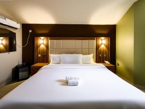 a bedroom with a large white bed with a towel on it at Aotel Hotel Lagos Ago in Lagos