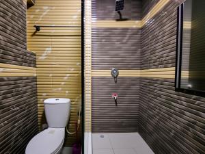 a bathroom with a toilet and a wooden wall at Aotel Hotel Lagos Ago in Lagos