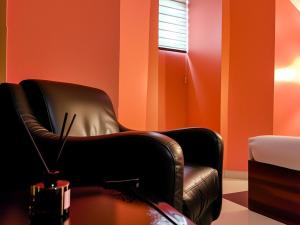 a black chair in a room with orange walls at Aotel Hotel Lagos Ago in Lagos +25 photos