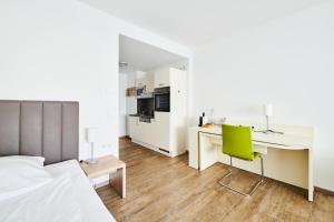 a bedroom with a bed and a desk with a green chair at ADAPT APARTMENT HOTEL Giessen in Gießen