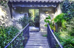 a wooden walkway leading to a door in a garden at L'Amandari - Provence holidays - Chambres d'hôtes avec jardin, piscine, jacuzzi, climatisation in Le Plan-de-la-Tour