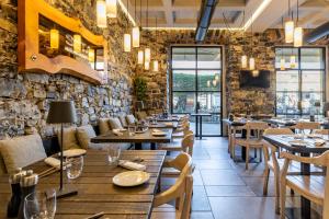 a restaurant with wooden tables and chairs and a stone wall at Seta Hotel in Bellagio