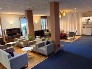 a waiting room with couches and chairs and tables at Le Grand Hôtel de Mayenne - Logis hôtels restaurant in Mayenne