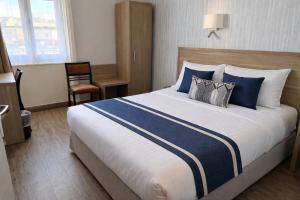 a bedroom with a large bed with blue and white pillows at Le Grand Hôtel de Mayenne - Logis hôtels restaurant in Mayenne +14 photos