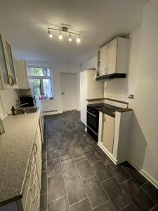 a kitchen with white cabinets and a tile floor at Villa Katry in Augustenborg