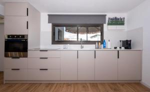 a white kitchen with a sink and a window at לב המעיין- סוויטה מושלמת עם ג'קוזי במושב פסטורלי in Reẖov