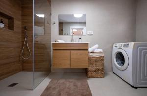 a bathroom with a washing machine and a sink at לב המעיין- סוויטה מושלמת עם ג'קוזי במושב פסטורלי in Reẖov