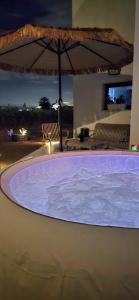 a large hot tub with an umbrella in a resort at לב המעיין- סוויטה מושלמת עם ג'קוזי במושב פסטורלי in Reẖov