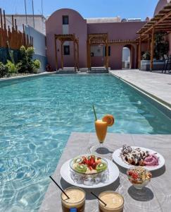 a table with food and drinks next to a swimming pool at Terra Nera Suites in Perivolos