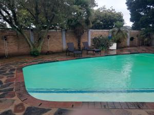 a large swimming pool with chairs in a yard at B&P Guesthouse in Boksburg