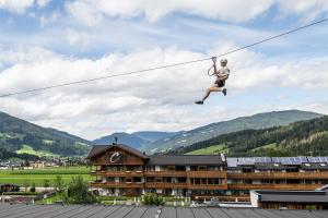 a person is jumping on a zip line at almlust - hotel, apartments, chalets in Flachau