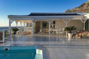 a house with a swimming pool next to the ocean at The Seaside View in Simonʼs Town