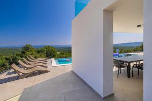eine Terrasse mit Stühlen und einem Tisch sowie ein Pool in der Unterkunft Villa ELEVATION in Vrh