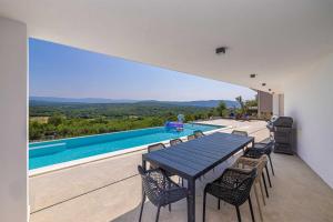 ein Haus mit Tisch und Stühlen und einem Swimmingpool in der Unterkunft Villa ELEVATION in Vrh