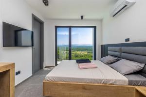 ein Schlafzimmer mit einem großen Bett und einem großen Fenster in der Unterkunft Villa ELEVATION in Vrh