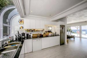 a kitchen with white cabinets and a large window at The Seaside View in Simonʼs Town