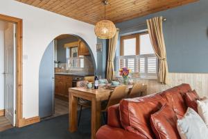 a living room with a table and a couch at Bay View - holiday cottage by the sea with stunning views in Pendine