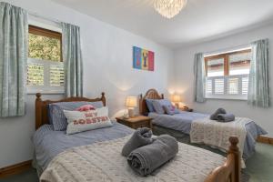 a bedroom with two beds and two windows at Bay View - holiday cottage by the sea with stunning views in Pendine