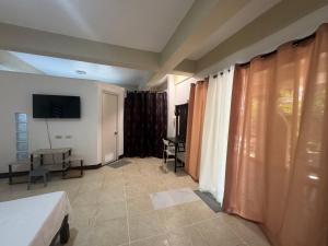 a room with a bed and a tv and curtains at Boracay Garden Retreat in Boracay