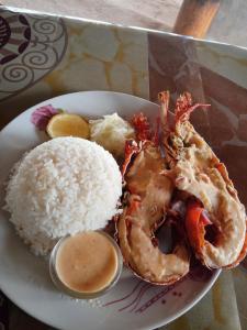 a plate of food with rice and shrimp and a side of sauce at Port Olry BBQ Table and Camping Side in Port-Olry