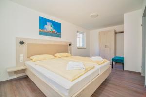 a bedroom with a large white bed with yellow pillows at BSW Ferienwohnungen Hiddensee in Hiddensee